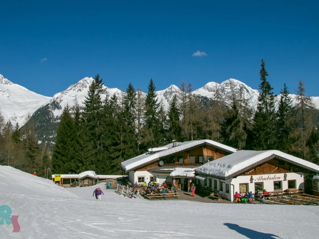 Skihütte vor der verschneiten Bergkulisse.